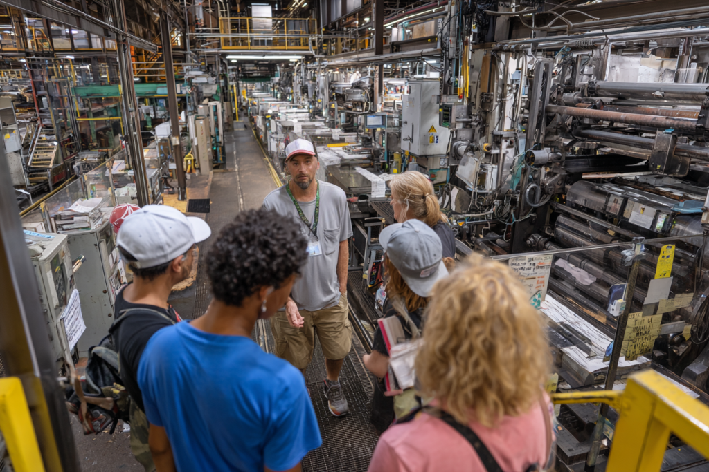 Workers listening inside a dense industrial space.